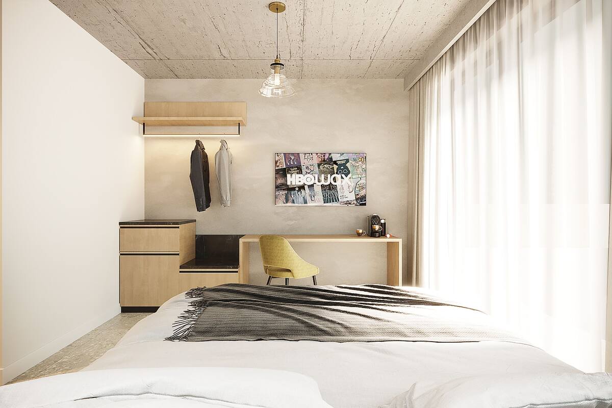 A modern bedroom with a bed, desk, chair, and a wall-mounted light fixture.