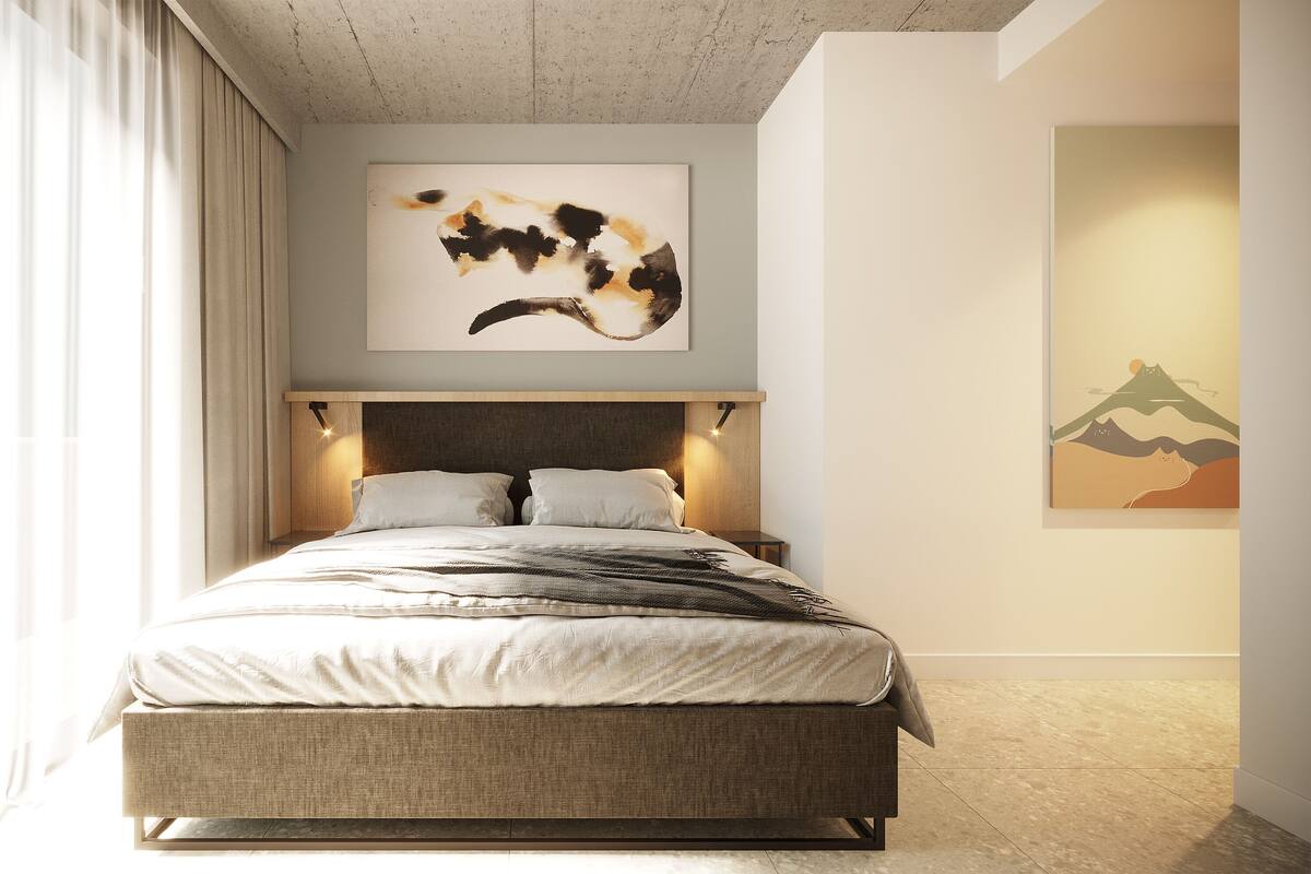 A modern bedroom with a large bed, a headboard with integrated lighting, a wall-mounted abstract painting, and a framed picture of a mountain.