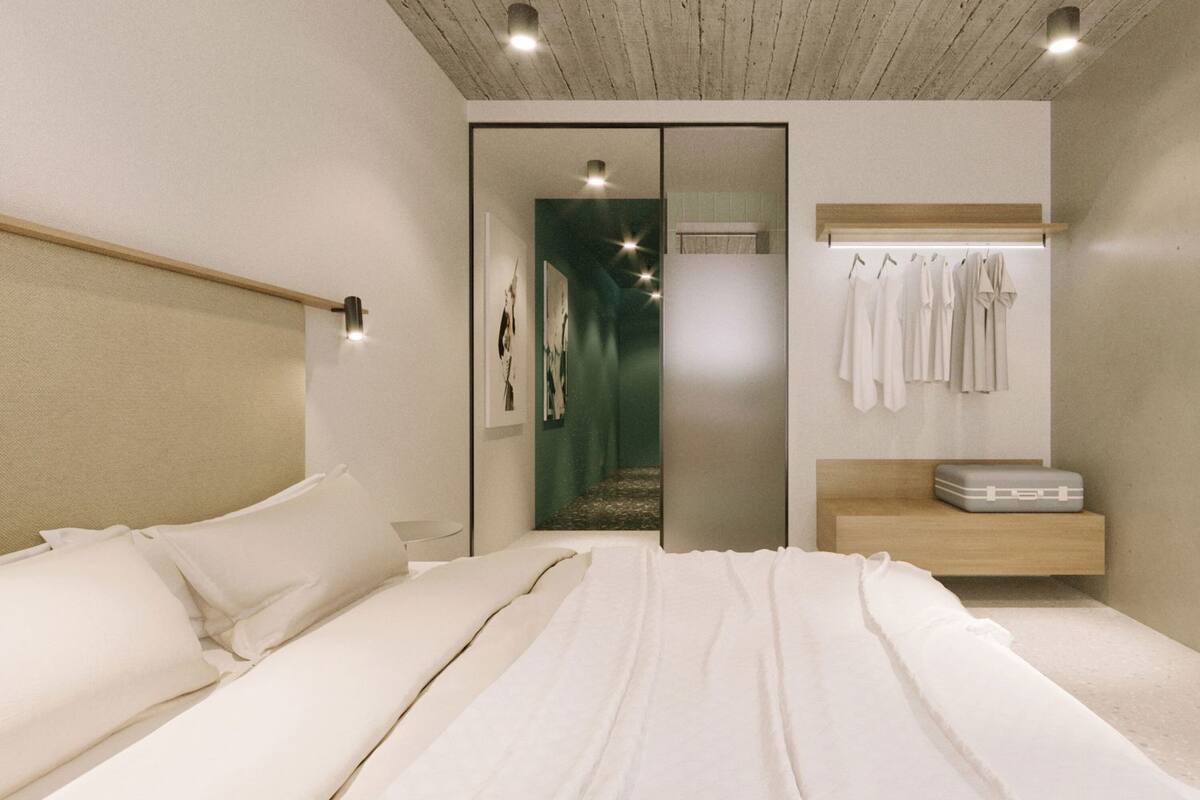 A bedroom with a bed, a bedside table, a mirror, and a wardrobe.