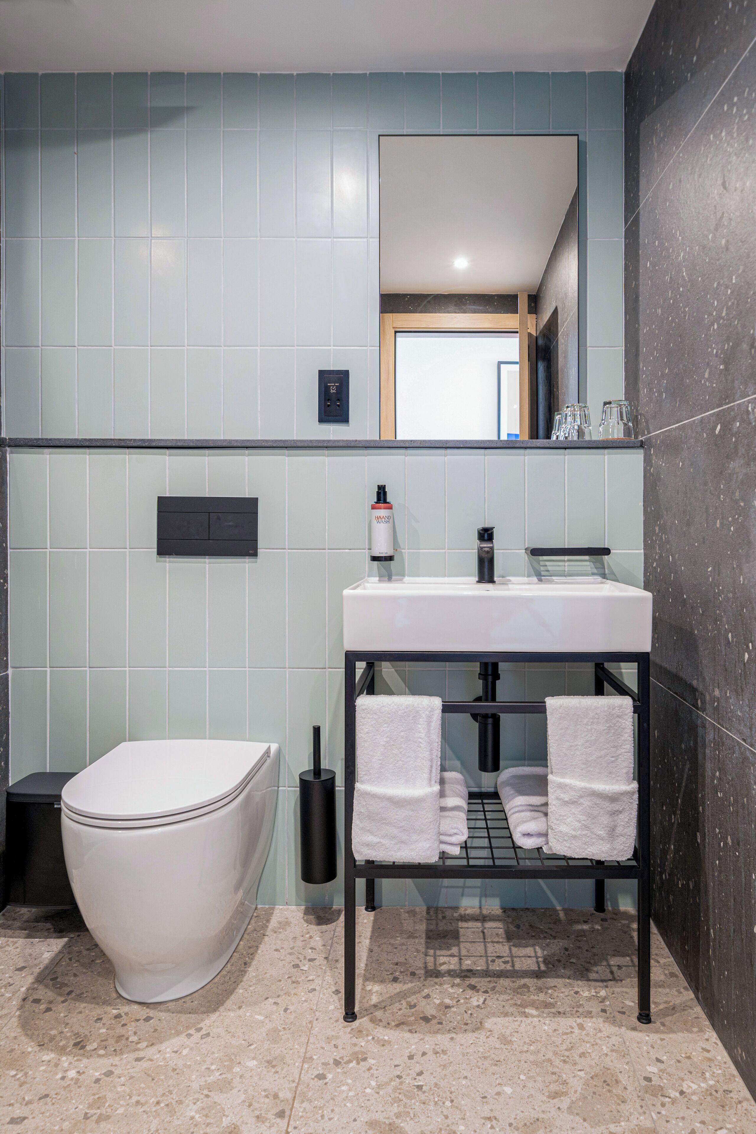 A modern bathroom with a white toilet, a sink with a black countertop, and a mirror above the sink.