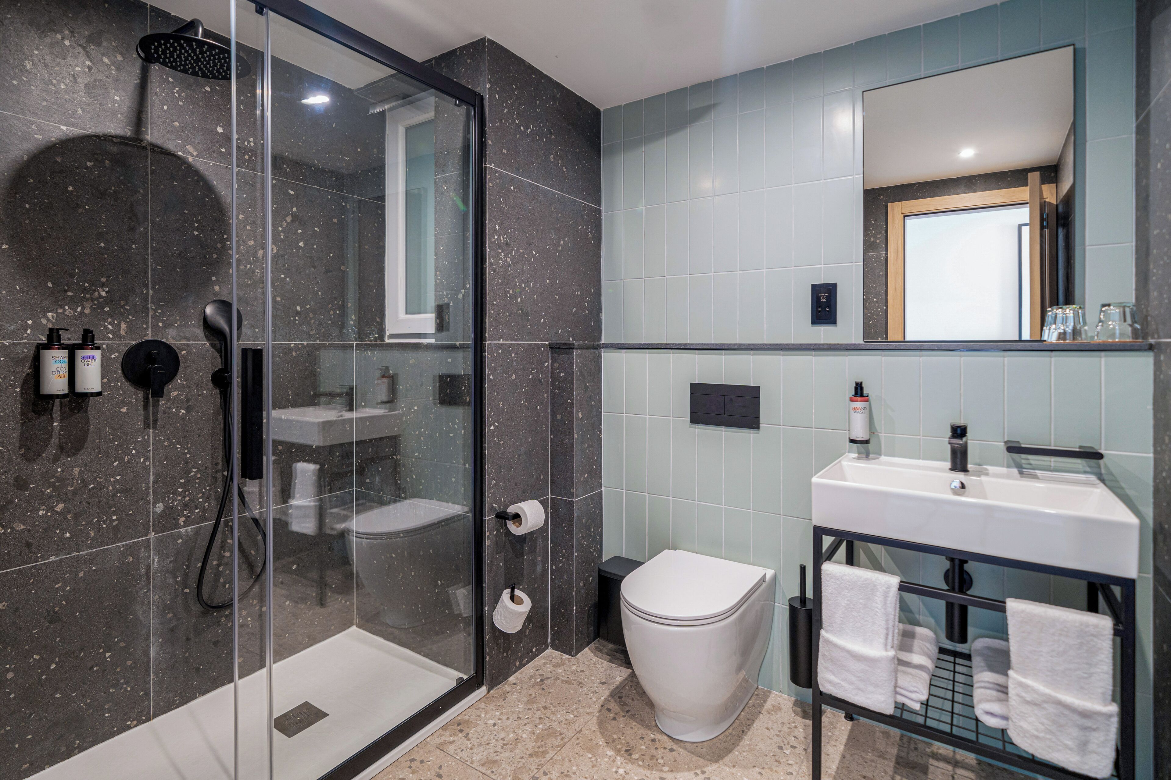 A modern bathroom with a glass-enclosed shower, a white toilet, and a sink with a mirror above it.