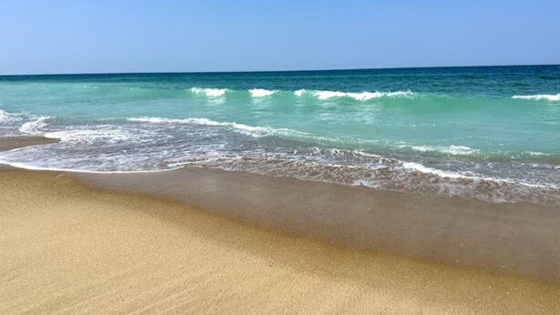 A beach with clear turquoise water and a sandy shore. - Sand Life - Pelican's Northern Nest -Pet Friendly! (Kill Devil Hills)