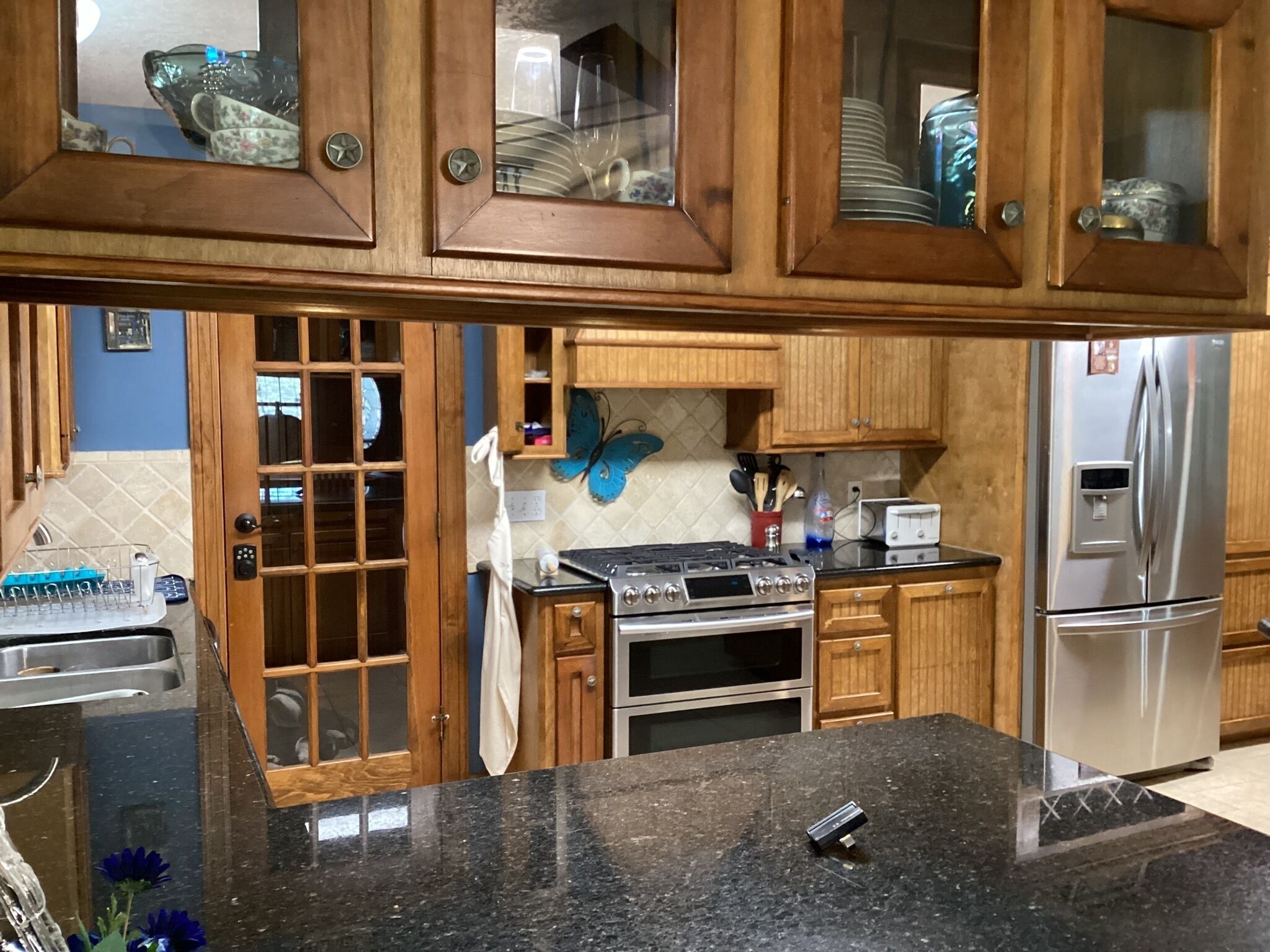 A kitchen with wooden cabinets, a stainless steel refrigerator, a stove, and a sink.