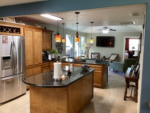 Enjoy cooking in this well-equipped kitchen with a central island, stainless steel appliances, and pendant lighting.