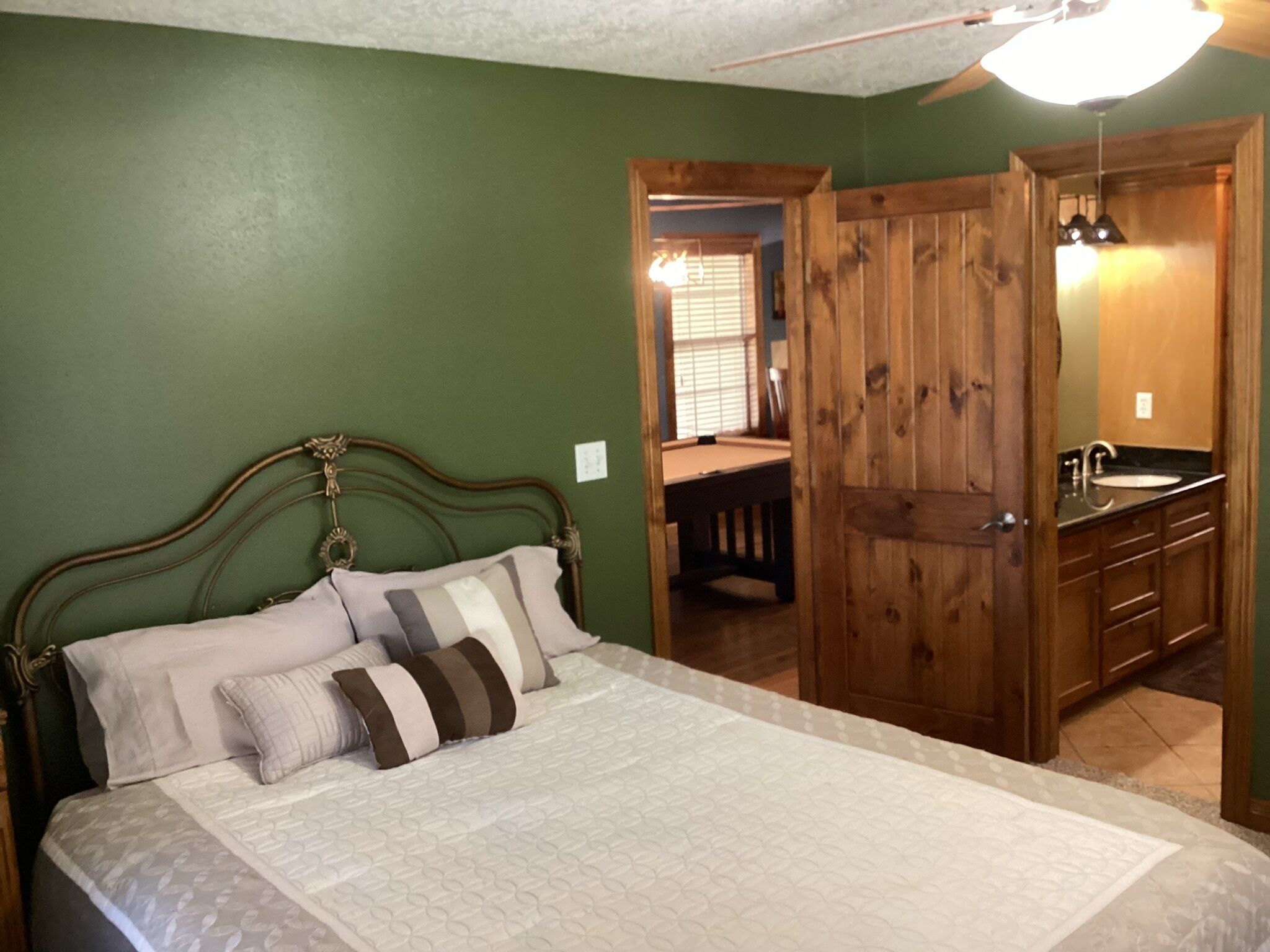 A bedroom with a bed, a wooden wardrobe, and a bathroom with a sink.
