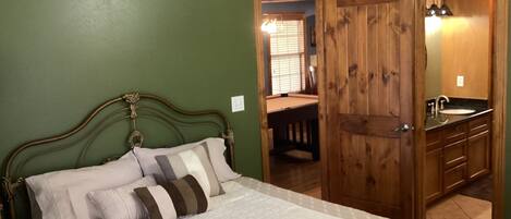 A bedroom with a bed, a wooden wardrobe, and a bathroom with a sink.