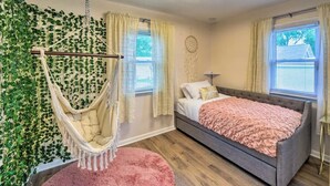 A bedroom with a bed, a hanging chair, a dreamcatcher, and a wall covered with green plants. - *New* < 3 Miles to Beach + Casino + Zoo + Shopping! (Michigan City)