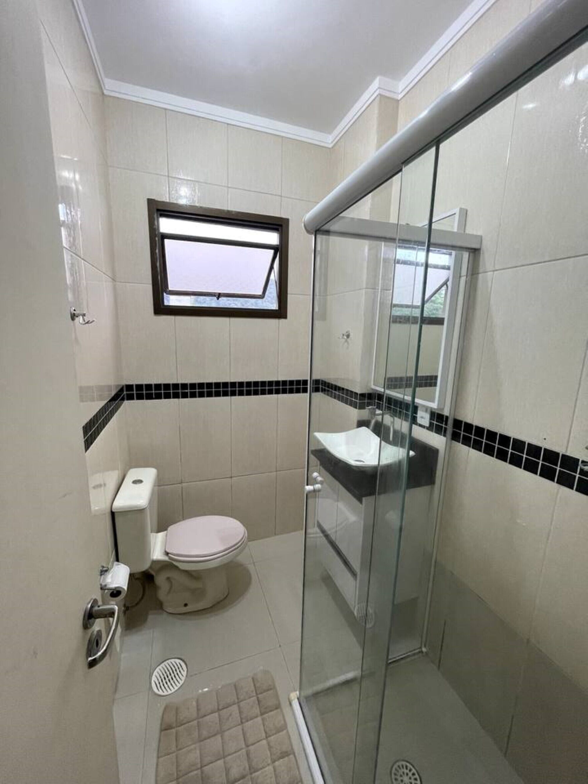 A compact bathroom with a toilet, sink, and shower area.