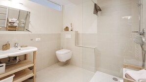 Ein modernes Badezimmer mit Duschkabine aus Glas, einem weißen Waschbecken und einer Toilette.