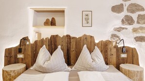 Ein Schlafzimmer mit einem hölzernen Kopfteil, zwei Nachttischen, einer Ablage und einem Regal mit Büchern sowie einem gerahmten Bild an der Wand.