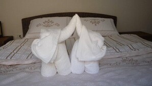 A bed with a striped bedspread and two towels arranged in a heart shape. - Villa Ban Rim Nam 50c (Ko Chang)
