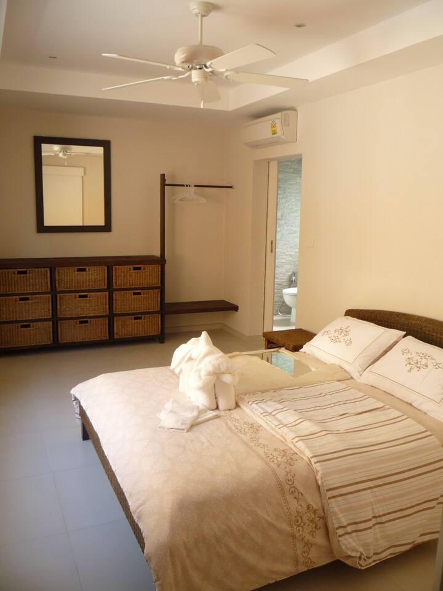 A bedroom with a bed, a ceiling fan, a wardrobe, a mirror, and a window.