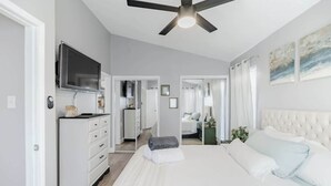 Une chambre d’hôtel moderne dotée d’un grand lit, d’un ventilateur de plafond, d’une télévision et donnant sur la cuisine.
