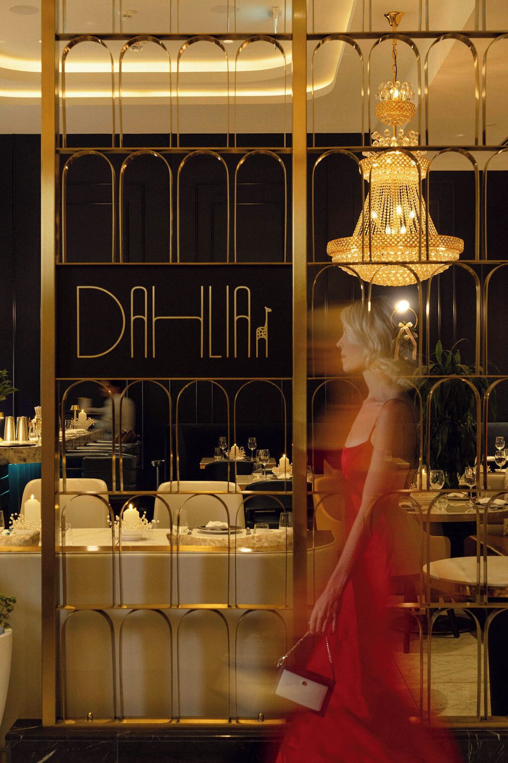 Ein Restaurantinneres mit einem Schild mit dem Schriftzug DAHLIA und einer Kristallleuchtre.
