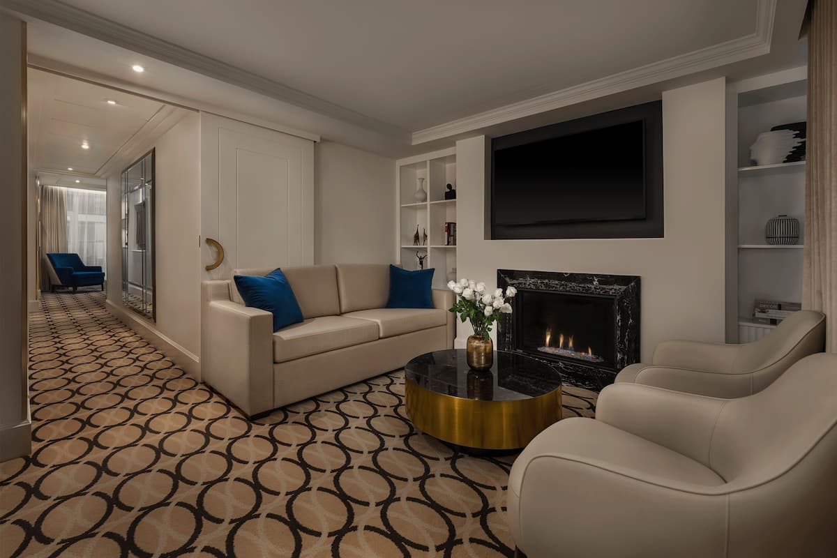 A modern living room with a beige sofa, blue pillows, a round coffee table, and a fireplace.