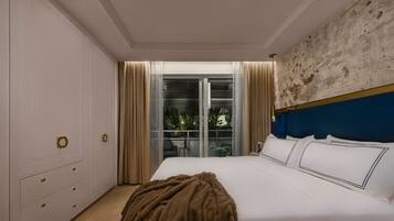 Un dormitorio con una cama grande, un armario con tiradores dorados, vista al exterior a través de una puerta de cristal y una pared azul decorativa.