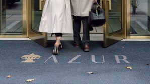 Una puerta giratoria con un panel de vidrio, un marco de metal y un letrero con la palabra "AZUR" en el suelo.