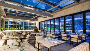 Un restaurante con techo de vidrio, mesas al aire libre y vistas de la ciudad.
