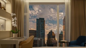 Una habitación de hotel con un ventanal grande, un escritorio, una silla y un sillón azul.