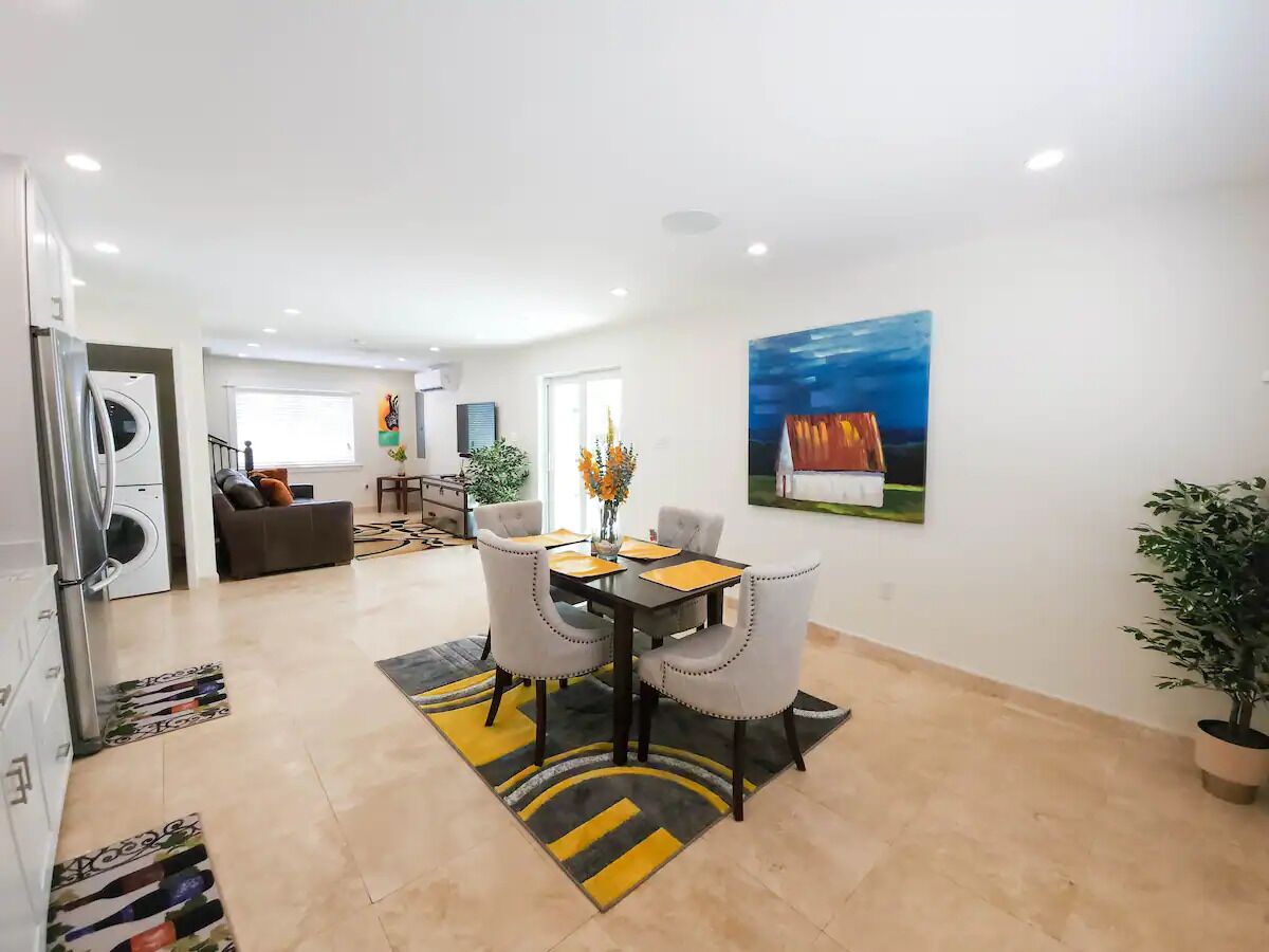 A modern living room with a dining area, a kitchen, and a laundry room.
