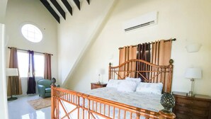 Ein Schlafzimmer mit einem hölzernen Bett, einem Nachttisch, einem Sessel und einem Fenster mit Vorhängen.