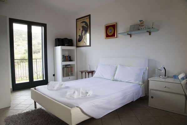 Une chambre à coucher comprenant un lit, une table de chevet, une bibliothèque et une fenêtre donnant sur un paysage agréable.