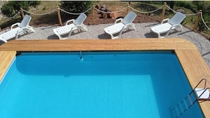 A rectangular swimming pool with a wooden deck and white lounge chairs around it. - Villa Lina.Independent, with swimming pool and view of the Aeolian islands (Caronia)