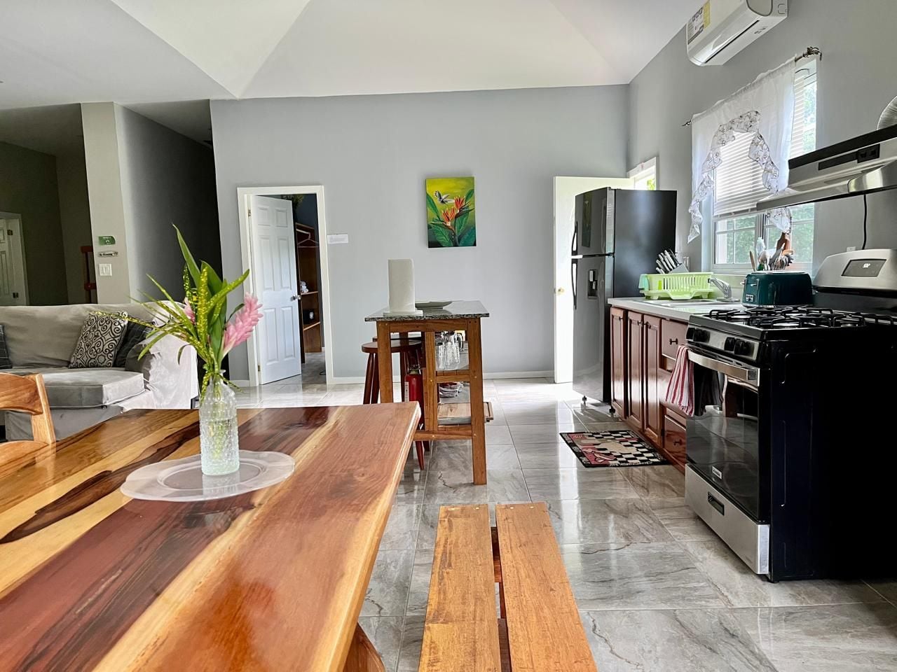 Una cocina moderna con estufa, horno y comedor con una mesa de madera y bancos.