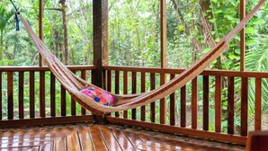 A hammock on a wooden deck with a view of a forest. - The Cabins at Monkey Fall (San Ignacio)