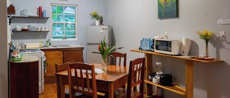 A compact kitchen with a dining area, a refrigerator, a microwave, and a coffee maker.