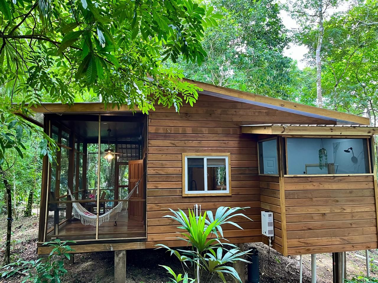 Una cabaña de madera con una hamaca, una ventana y una puerta.