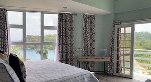 Enjoy a serene lake view from the comfort of this spacious room, featuring a large bed, desk, and balcony access.