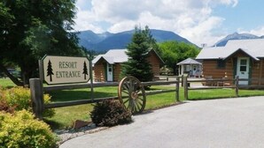 A resort entrance with a sign, wooden fence, and a cart.