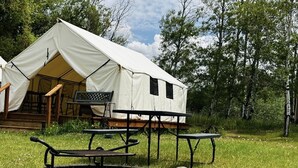 A white tent with a porch and a table and chairs set up in front.