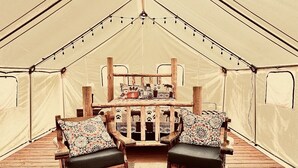 A tent with a central table and two chairs with patterned cushions.