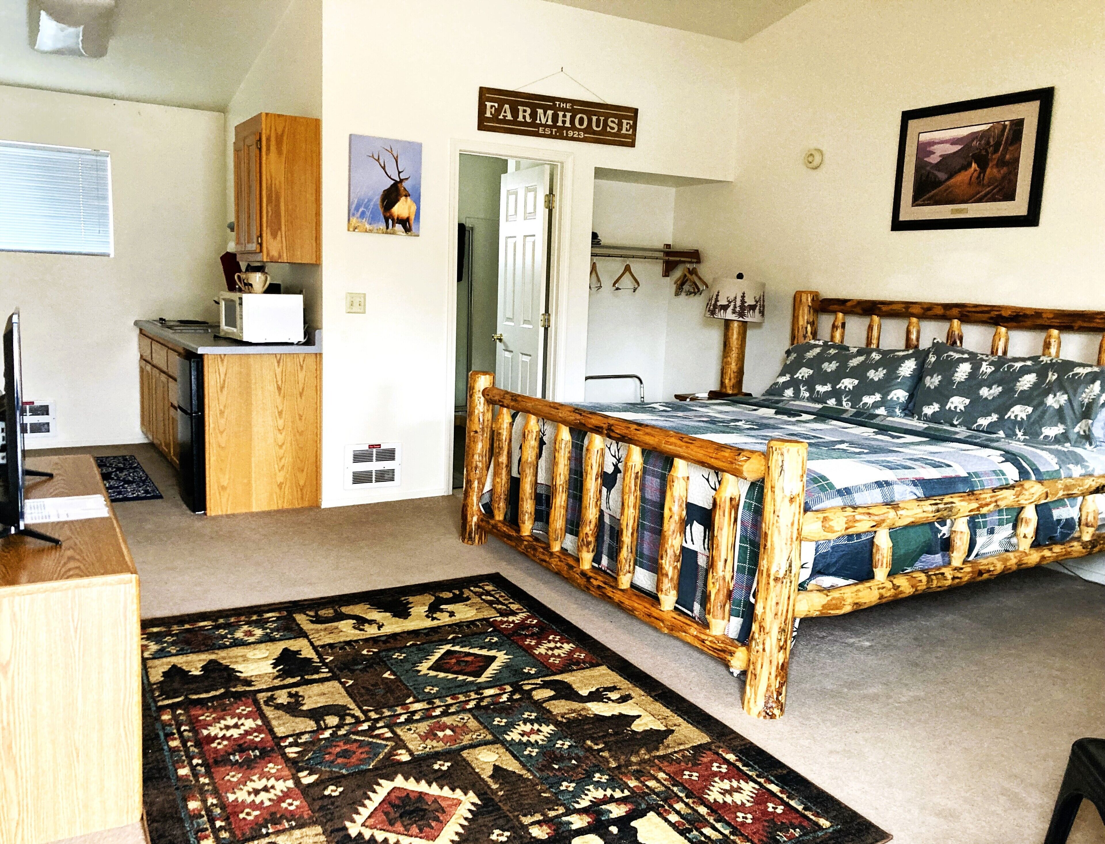 A bedroom with a bed, a desk, a chair, a rug, and a sign that reads "The Farmhouse".
