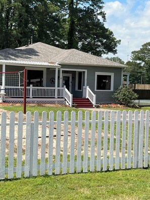 A two-story house with a porch, a small front yard, and a white picket fence.