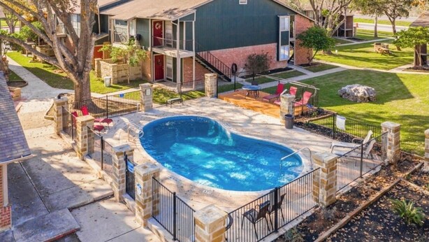 Una propiedad residencial con piscina, patio cubierto y jardín trasero cercado.