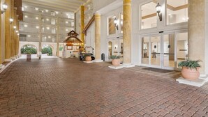 A spacious lobby with a brick floor, multiple columns, and a central staircase.