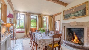 Una sala da pranzo con camino, travi in legno e un tavolo apparecchiato per sei persone.