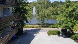 Un bâtiment doté d’un balcon, d’une fontaine et d’un lac en arrière-plan.
