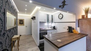 Une cuisine moderne avec des meubles blancs, un plan de travail en bois et une horloge au mur.