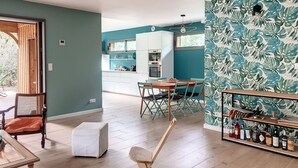 A modern kitchen with white cabinets, a dining area with a wooden table and chairs, and a living space with a sofa and a coffee table. - 50 m from the lake, new wooden house - ideal family (Lacanau)