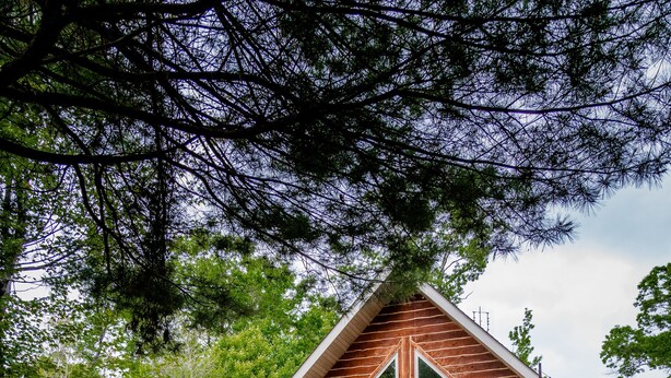 A hammock in a grassy area with a wooden cabin in the background.