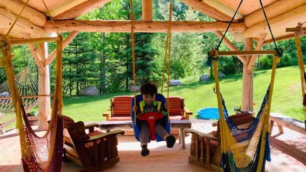 A wooden deck with a swing set, a hammock, and a table with chairs. - Cozy cottage trails, trout fishing & fireplace. (Marcell)