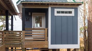 A wooden deck with a bench, a door with a 'M' sign, and a small window on a building.