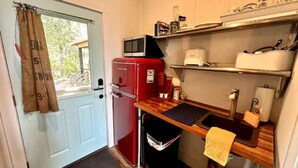 Una cocina compacta con un refrigerador rojo, un microondas y una encimera de madera.