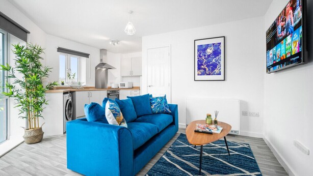 Un salon moderne avec un canapé bleu, une table basse et une grande fenêtre.