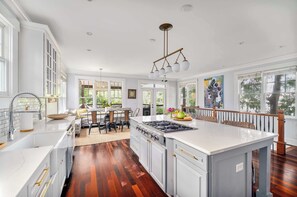A spacious kitchen with a large island, white cabinetry, and a wooden floor.