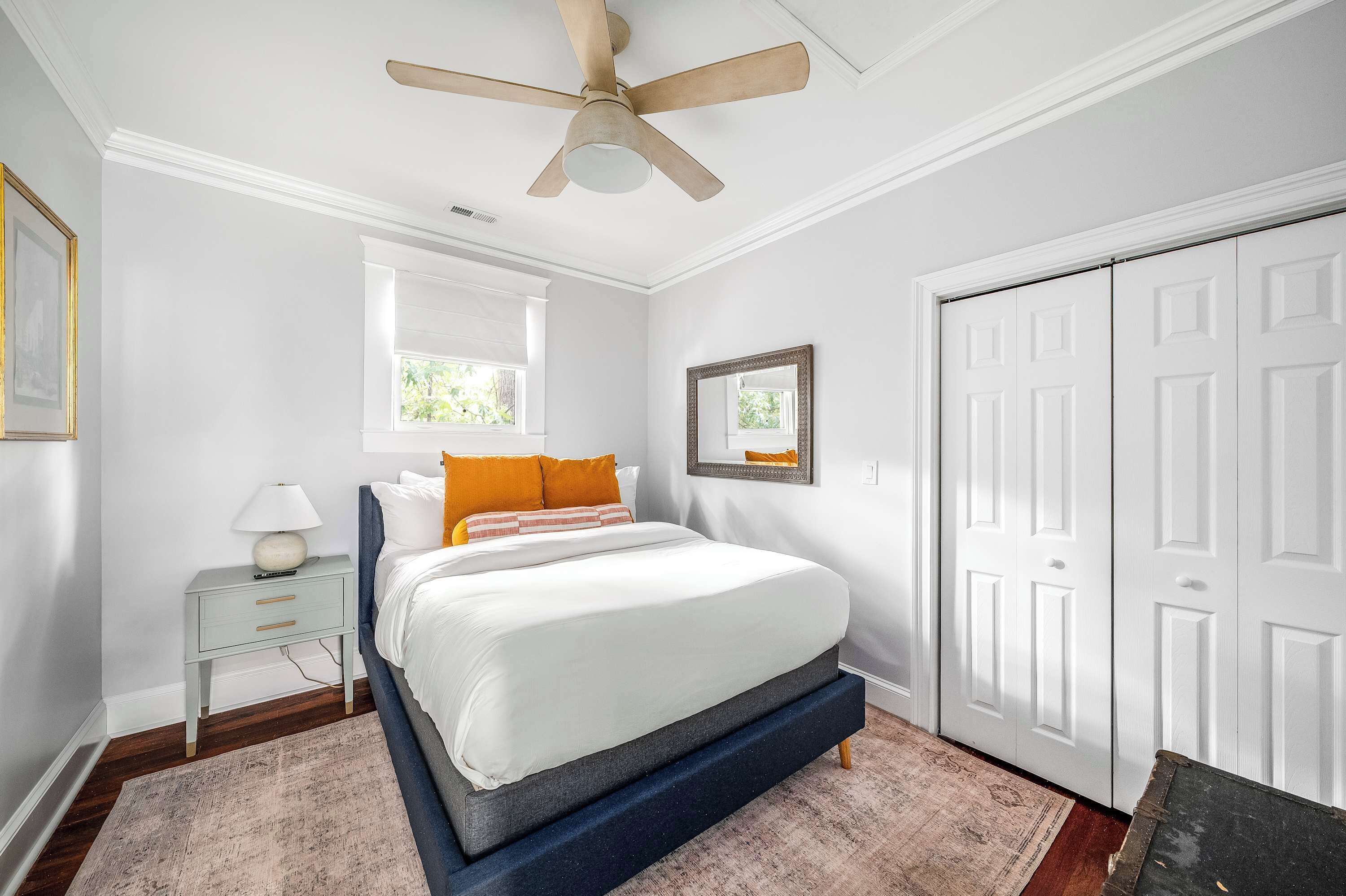 A bedroom with a bed, nightstand, and a ceiling fan.